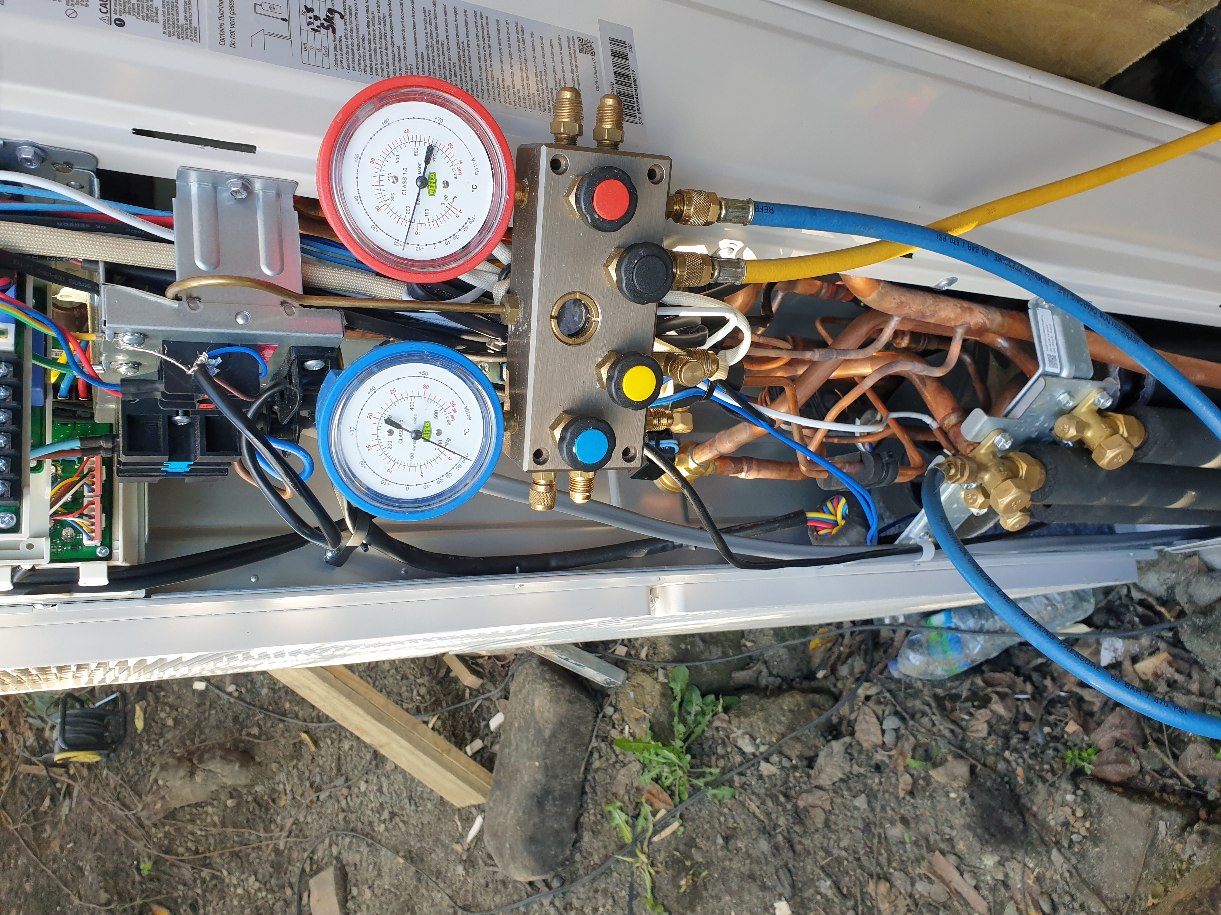 Pressure manifold gauges hooked up to outdoor condenser service valves checking system pressure
